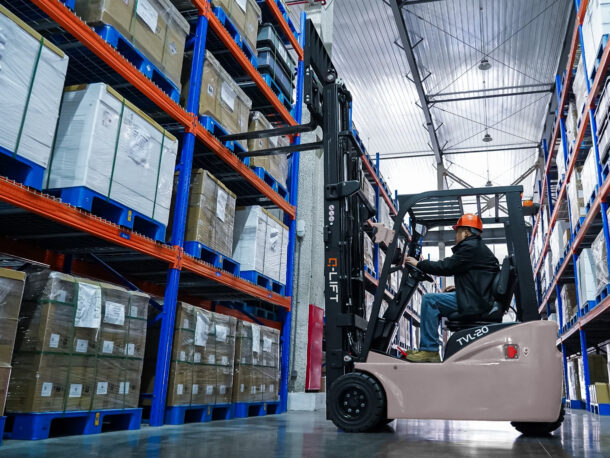 Elektryczny wózek widłowy trójkołowy Q-LIFT TVL by WDX podczas pracy w magazynie