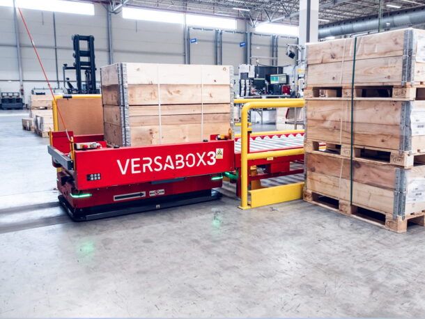 Robot AMR odbiera ładunek z przenośnika rolkowego